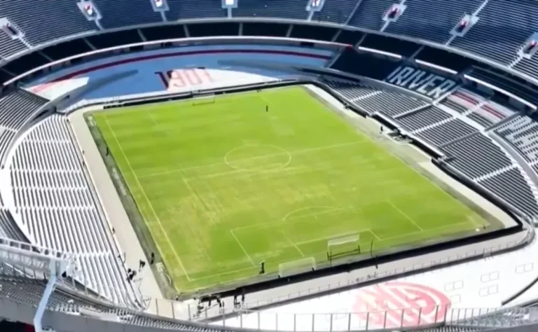 Vista aérea del campo de juego del estadio Monumental, mostrando sectores con arena y parches en el césped.