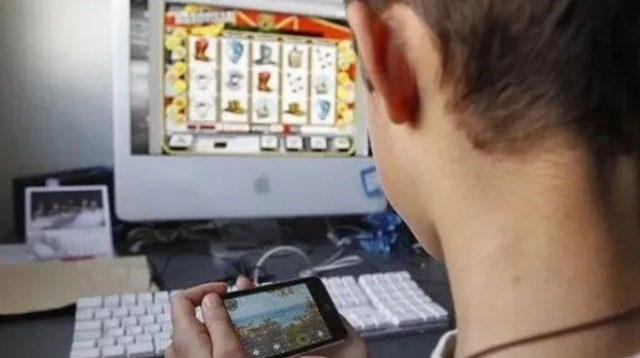 Ilustración de un niño con un celular y símbolos de apuestas tachados, representando la prevención de la ludopatía infantil